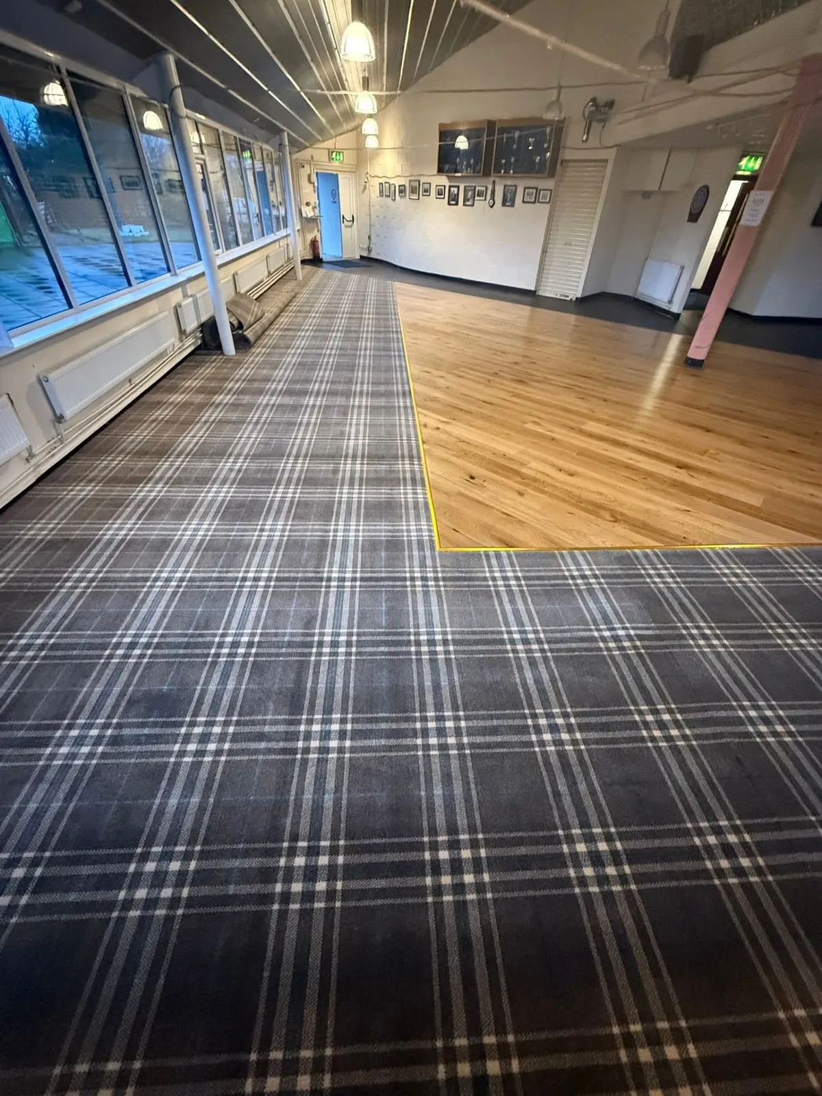 Large hall fitted with grey tartan carpet surrounding a wood floor area