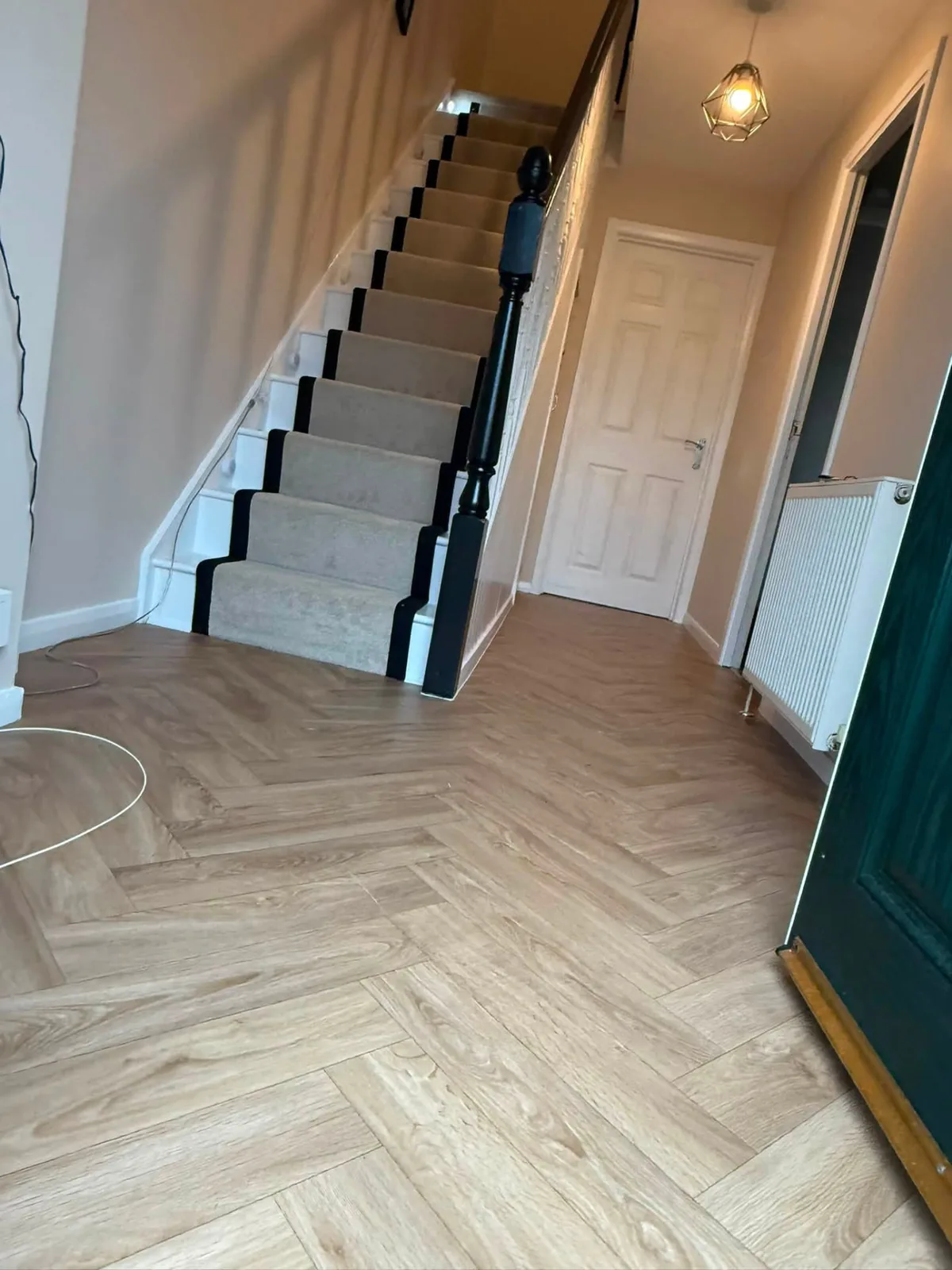 Finished hallway with herringbone floor and carpet stair runner