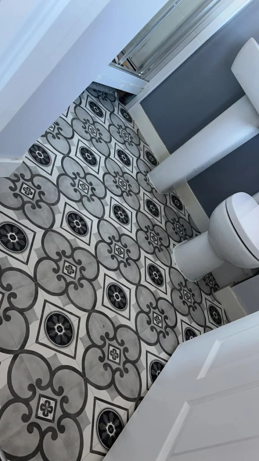 Black, grey and white patterned tile-effect floor in a bathroom