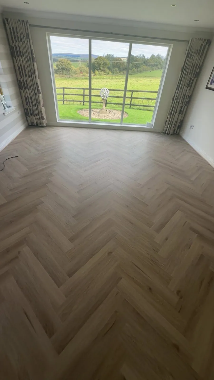 Light herringbone floor in a living room with large patio doors